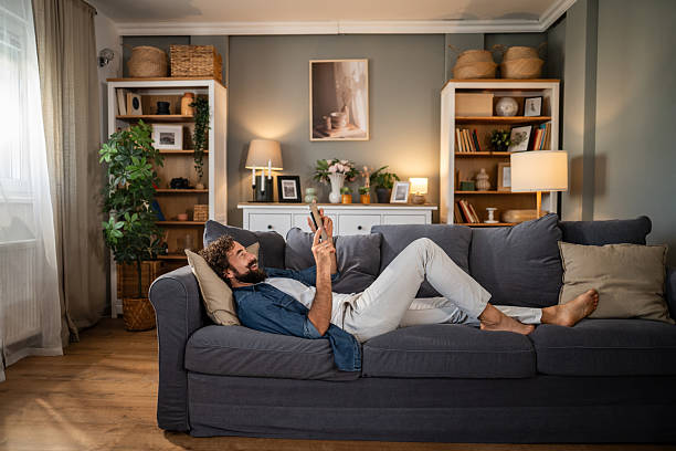 istock Young man relaxing on living room sofa using digital tablet 2236978743