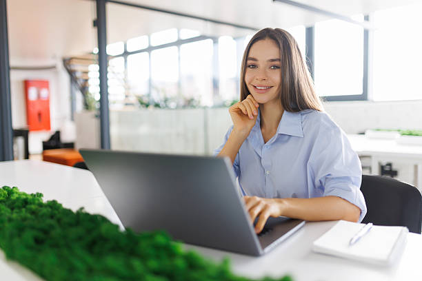 istock Young beautiful joyful woman smiling while working with laptop in office 2236981415