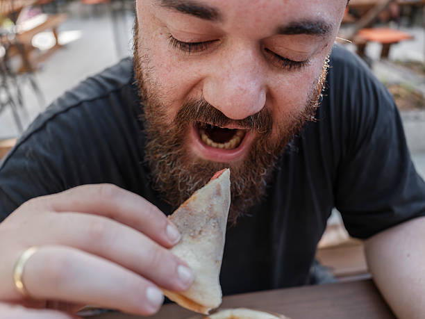 istock Young man eating delicious pizza at a restaurant 2236983845