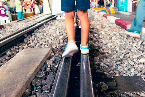 Young legs walking on railway on a train station