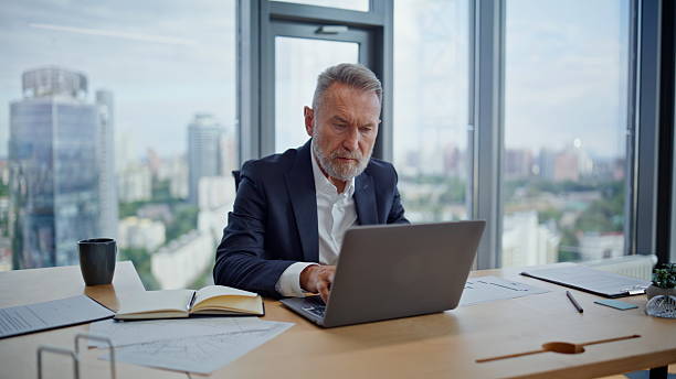 istock Mature manager looking laptop planning business project at workplace closeup. 2236985301