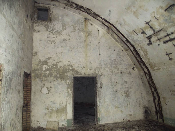 Front view of an abandoned brick building with broken windows and overgrown vegetation, illustrating urban decay and neglect.