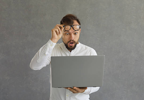 istock Man looking at screen of his laptop computer with expression of big shock on face 2236986909