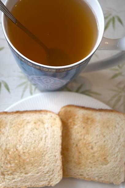Close-up of two slices of toast served on a plate with tea, representing breakfast and diet.