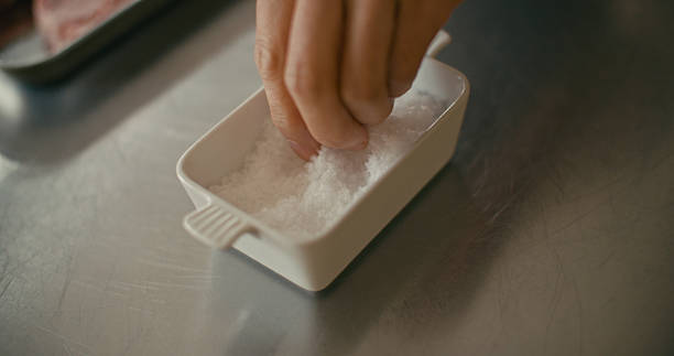 A close-up view of a hand picking sea salt flakes in a home kitchen.