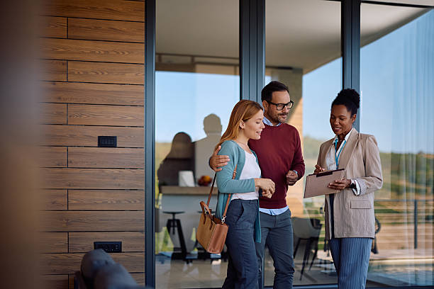 istock Smiling couple and their real estate agent analyzing paperwork during open house day. 2236990156