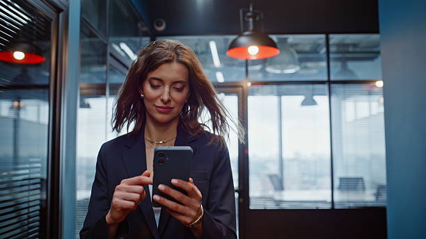 istock Smiling lady reading cellphone message walking hallway in elegant suit closeup. 2236991594