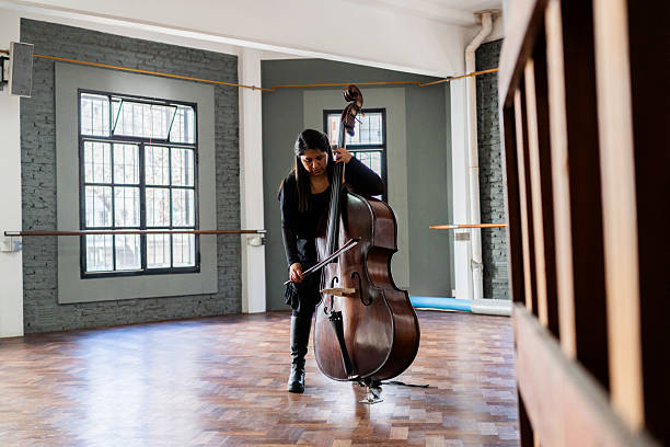 Talented young man in a suit playing double bass over abstract background. Contemporary art collage. Concept of music festival, creativity. Template for music event posters. Modern aesthetics