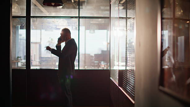 istock Silhouette manager talking cellphone in office corridor. Businessman finish call 2236994580
