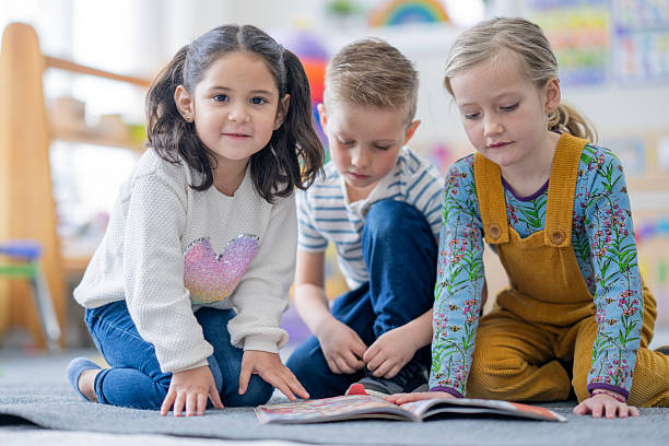 istock Three Diverse Children Read Together on Classroom Floor Exploring Books and Learning 2236995543