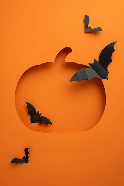 istock Creative vertical Halloween design featuring a pumpkin cutout with black bats on an orange background for seasonal decor 2236996015