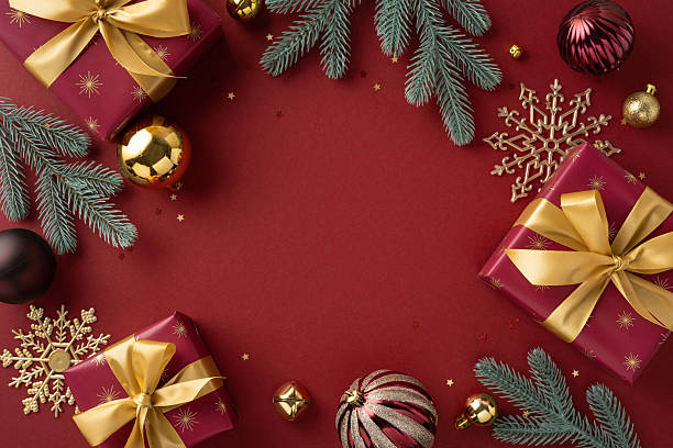 istock Festive arrangement of wrapped presents, pine branches, and ornaments on a red surface 2236996099