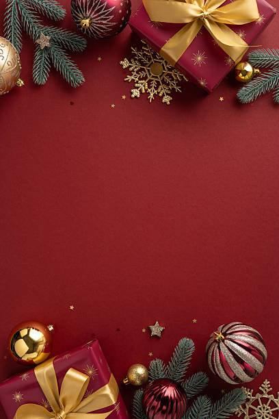 istock Holiday-themed vertical image featuring festive decorations including gifts, ornaments, and golden snowflakes on a rich red background, symbolizing Christmas and New Year's celebrations 2236996101