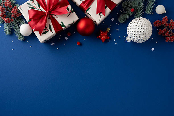 istock A festive layout with wrapped gifts, red ribbons, pine branches, and decorative ornaments on a deep blue background, evoking Christmas and New Year cheer 2236996113
