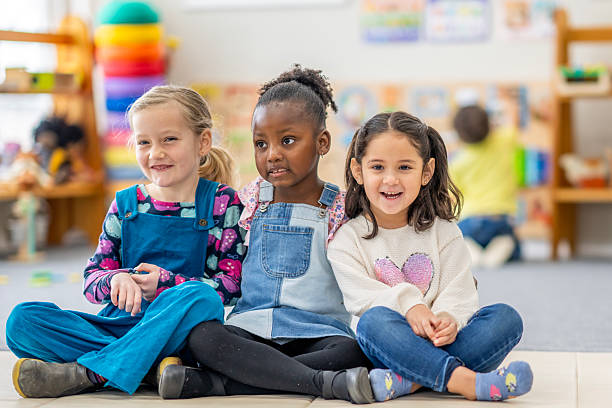 istock Three Diverse School Friends Sit Together Smiling in Bright Classroom Setting 2236996584