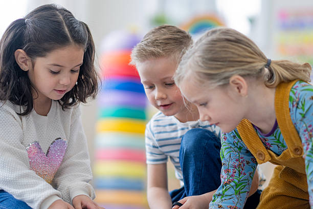 istock Three Diverse Kids Learning Together in a Bright Classroom, Sharing Focus and Friendship 2236996763