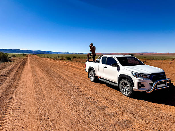 istock Photographer taking an image standing on a trunk of his car 2237000045