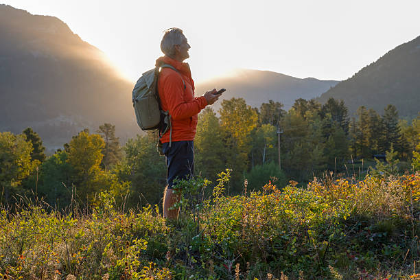 istock Man uses mobile phone in mountain meadow at sunrise 2237010407