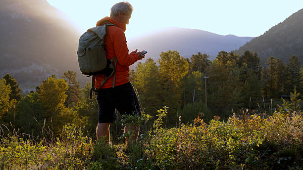 istock Man uses mobile phone in mountain meadow at sunrise 2237010421