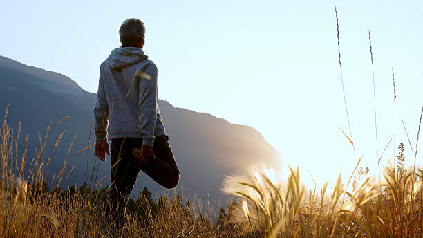 istock Man stands on one leg in mountain meadow 2237010483