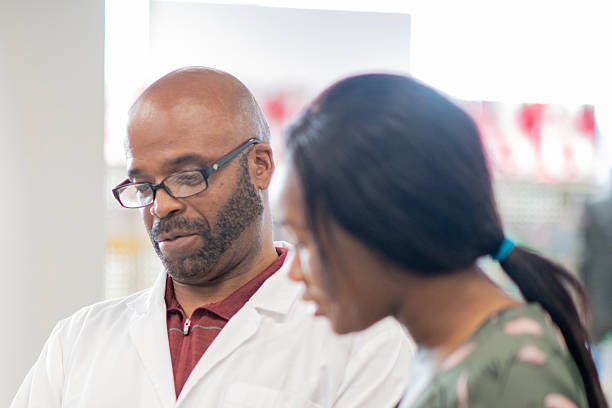 istock Pharmacist In White Coat Consults With Customer In A Bright Pharmacy Setting 2237012975