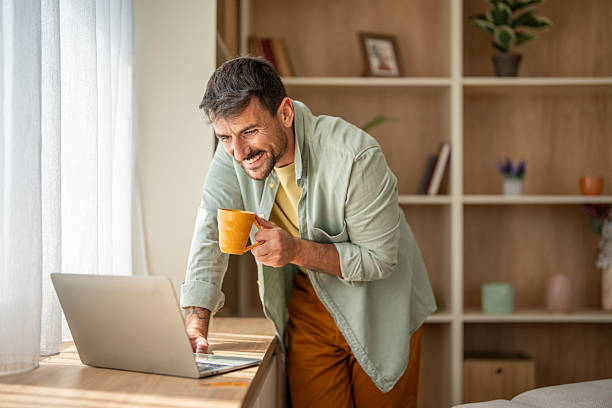 istock Smiling freelancer enjoying morning coffee while working on laptop at home 2237013684
