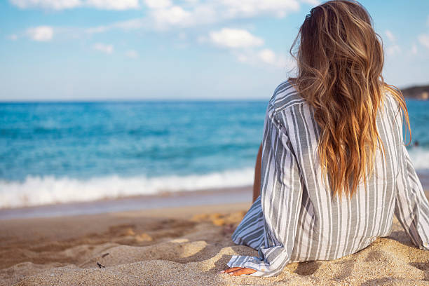 istock Back View of Woman Relaxing on a Tranquil Sandy Beach 2237013982