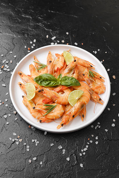 istock Shrimp with herbs and coarse salt on black surface for cooking background or seafood concept 2237014191