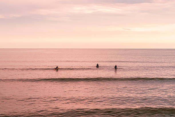 istock Surfers in the ocean at a pastel sunset 2237025411