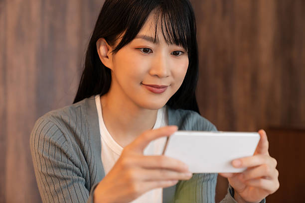 istock attractive asian woman using a smart phone ,watch a video 2237030352