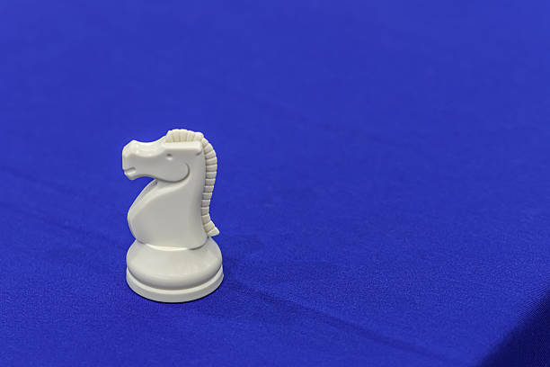 White chess horse on a blue mat. Space for text.