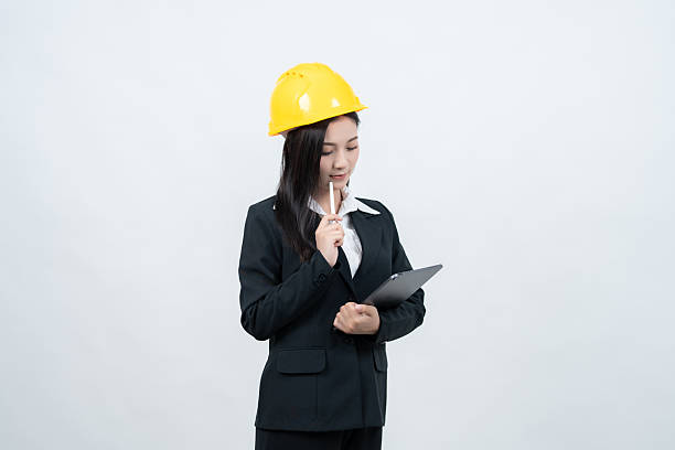 istock In a white background studio, an Asian female engineer dressed in a suit with a helmet confidently presents her vision for the future, emphasizing innovation and growth within the industry. 2237043899