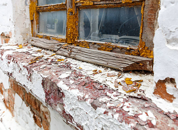 Smashed window blocked with corrugated iron, with wooden frame surrounded by peeled paint in a burnt-out Ancient Briton Hotel, Naseby, New Zealand