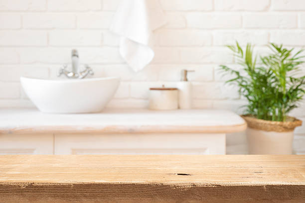istock Aged lightly lit wooden table top in front of rustic blurred bathroom interior background 2237051662