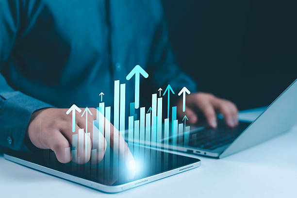 istock Businessman analyzing digital bar chart with growth arrows on tablet and laptop, concept of business analytics, financial growth, visualization, performance tracking, investment strategy, and digital 2237057325