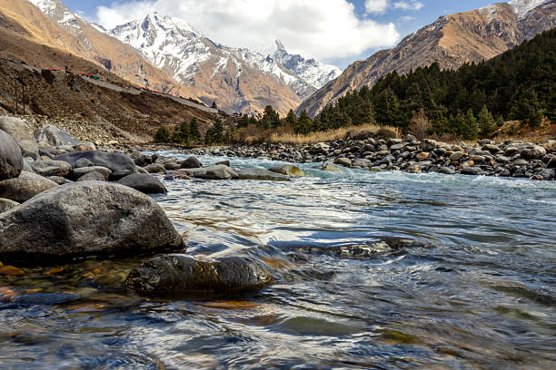 istock Mountain landscape featuring a clear river flowing through rocky terrain with snow-capped peaks and pine forests in the background, ideal for travel, adventure, environment, tourism, and nature themes 2237063368