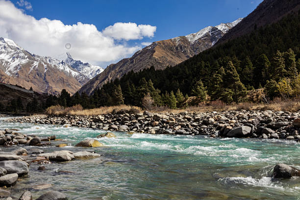 istock Mountain landscape featuring a clear river flowing through rocky terrain with snow-capped peaks and pine forests in the background, ideal for travel, adventure, environment, tourism, and nature themes 2237063378