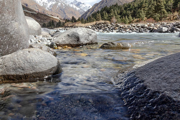 istock Mountain landscape featuring a clear river flowing through rocky terrain with snow-capped peaks and pine forests in the background, ideal for travel, adventure, environment, tourism, and nature themes 2237063428