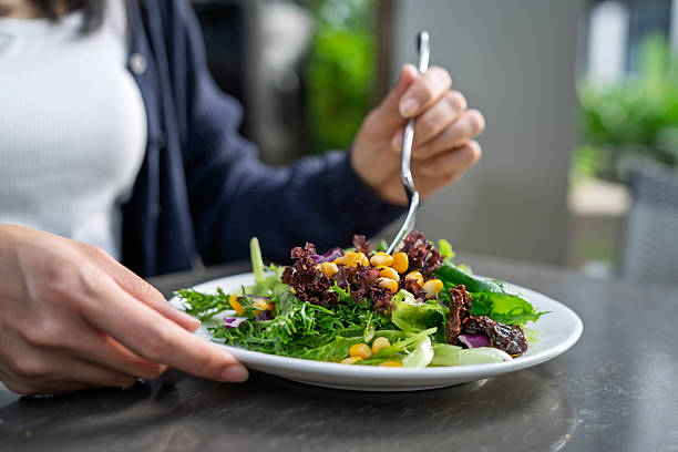 istock A woman eating fresh salad with corn and lettuce 2237069920