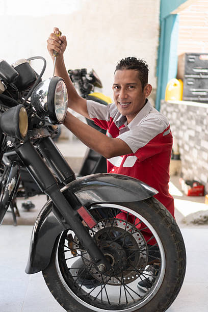 istock Mechanic smiling while repairing motorcycle in workshop 2237076461