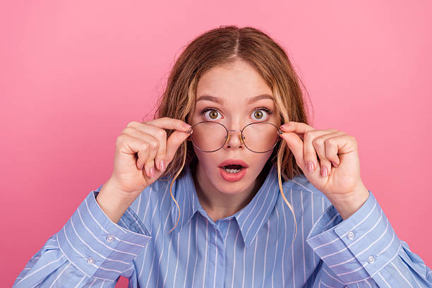 istock Surprised young woman with glasses adjusting frame on pink background 2237079755