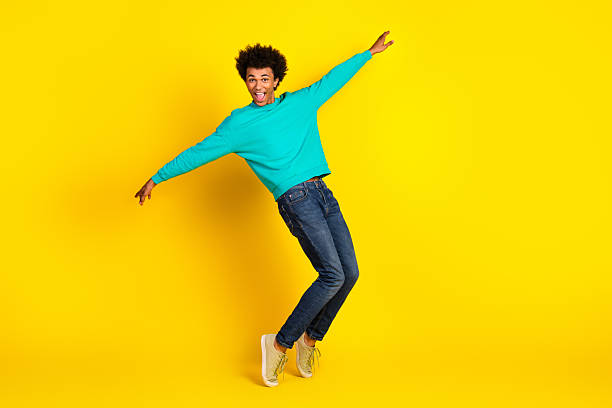 istock Energetic young man in a teal sweatshirt posing playfully against a vibrant yellow background expressing joy and style 2237080862