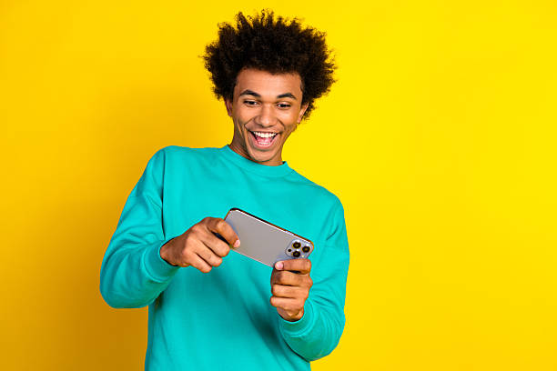 istock Excited young man using a smartphone against a yellow background showcasing casual style and cheerful energy 2237081005