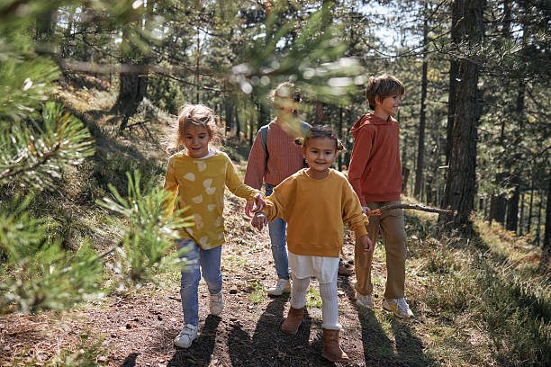 Group of happy children walking on a forest path, holding hands, and enjoying outdoor adventure