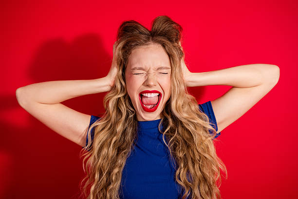 istock Young blonde woman with hands on head making an energetic expression against a solid red background, styled fashionably 2237081299