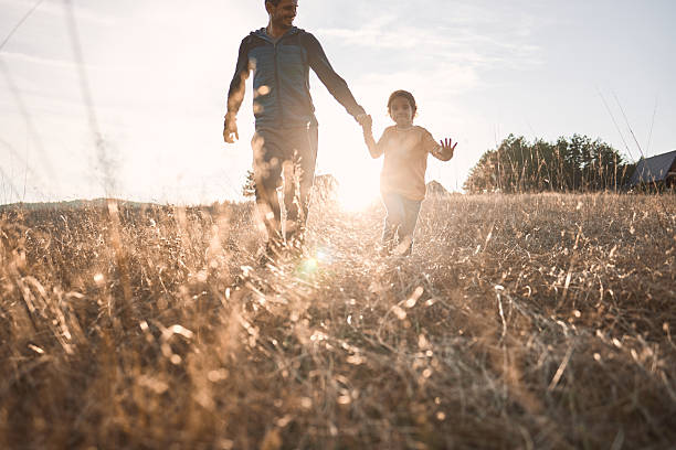 istock Father daughter walking hand in hand in sunny field 2237081352