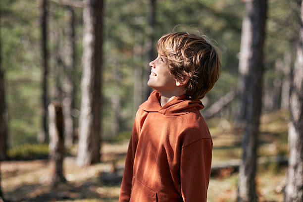 Young boy smiling looking up in a sunny woodland