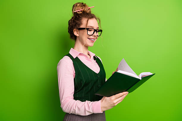 istock Smiling Young Student with Glasses Holding Open Book on Vibrant Green Background in Educational Scene 2237082532