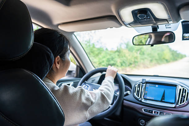 istock Woman driving a car on a road with greenery outside 2237082748