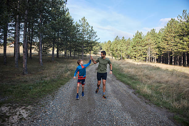 Young boy navigates wooden stumps outdoors under the supervision of a trainer, engaging in balance focused physical activity.